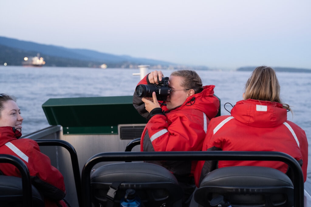 A passenger onboard a whale watching trip takes photos with her camera of the local scenery